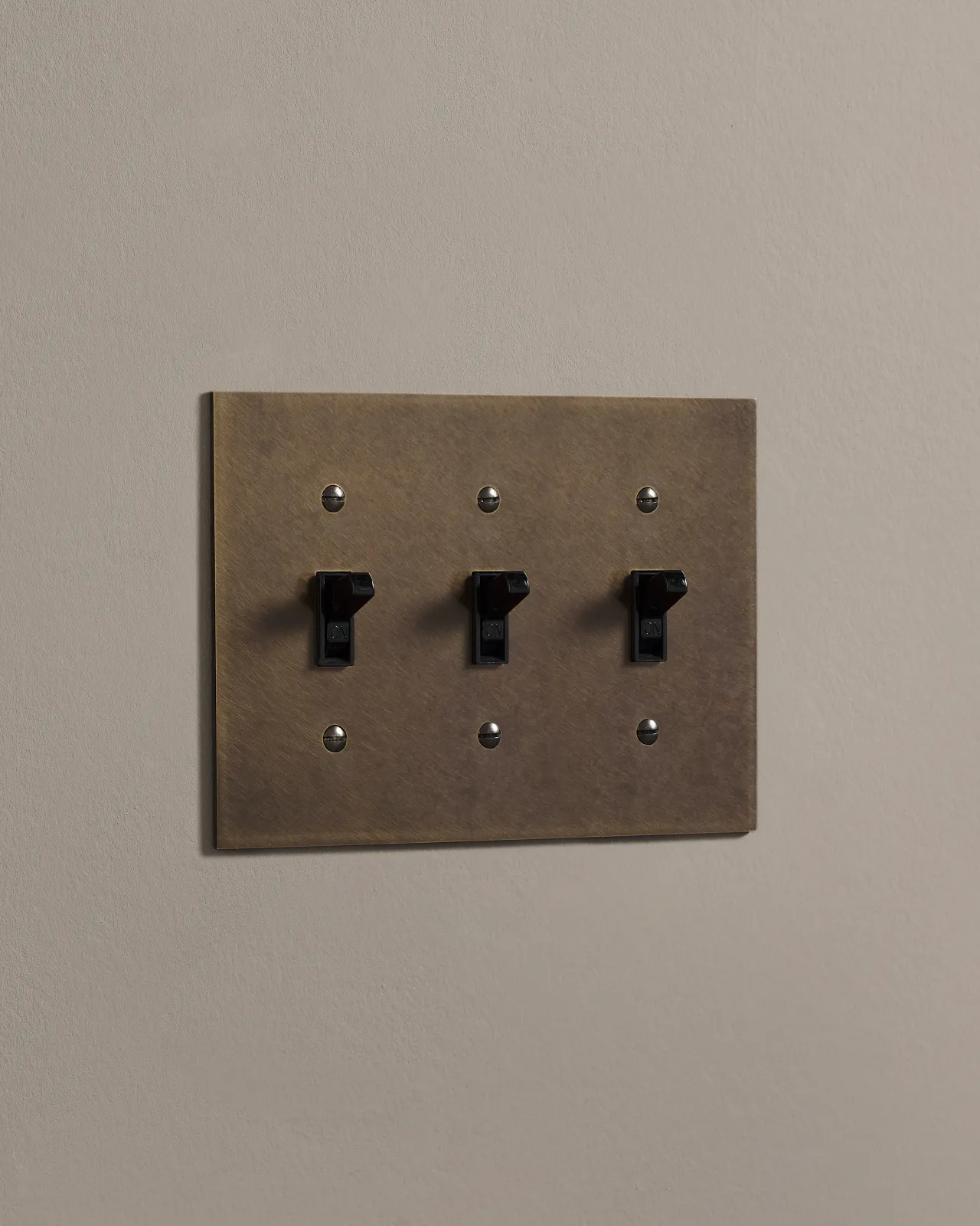 a side on shot of the toggle switch on an oxidised brass cover plate.