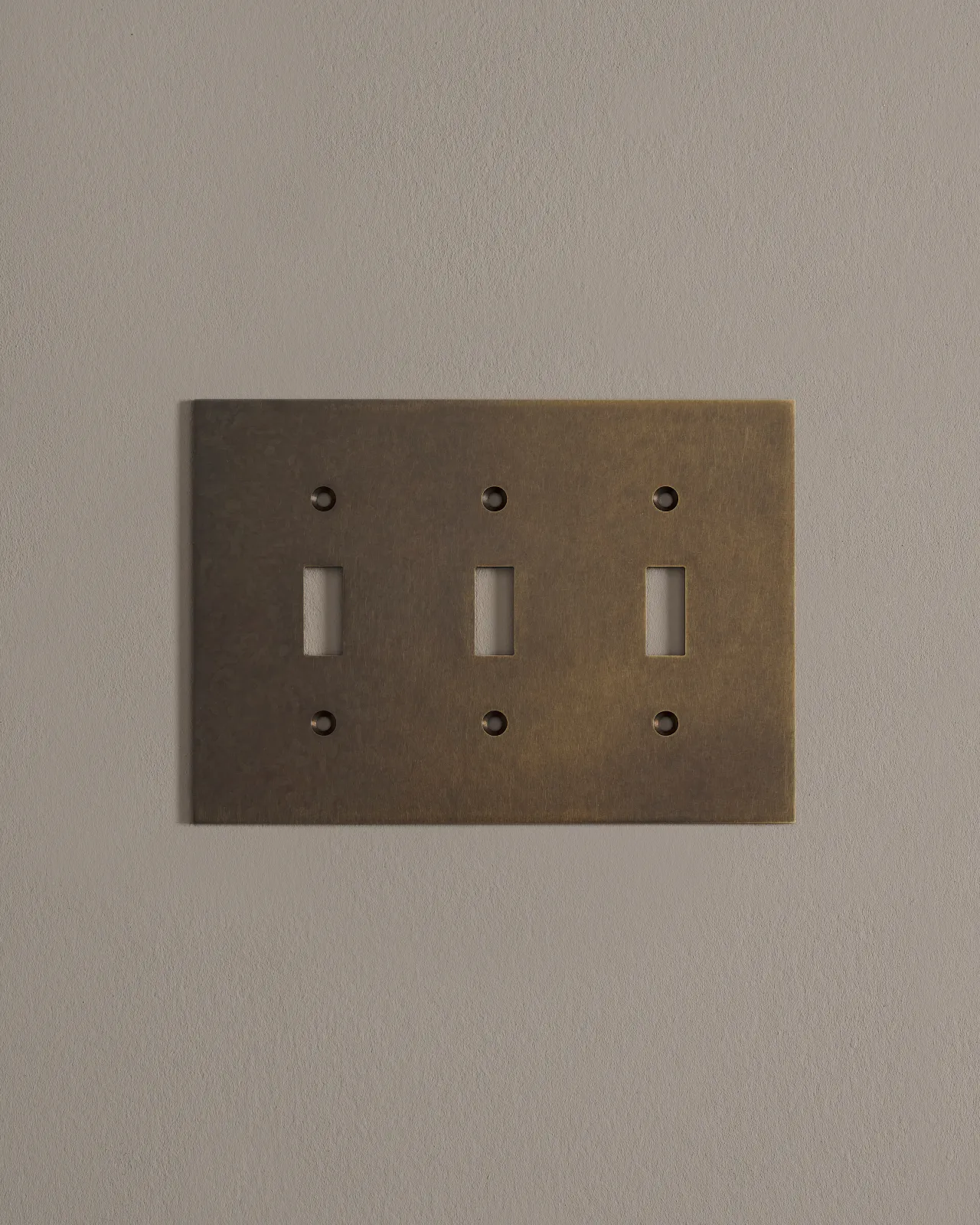 a front on shot of the toggle switch cover plate in oxidised brass finish.