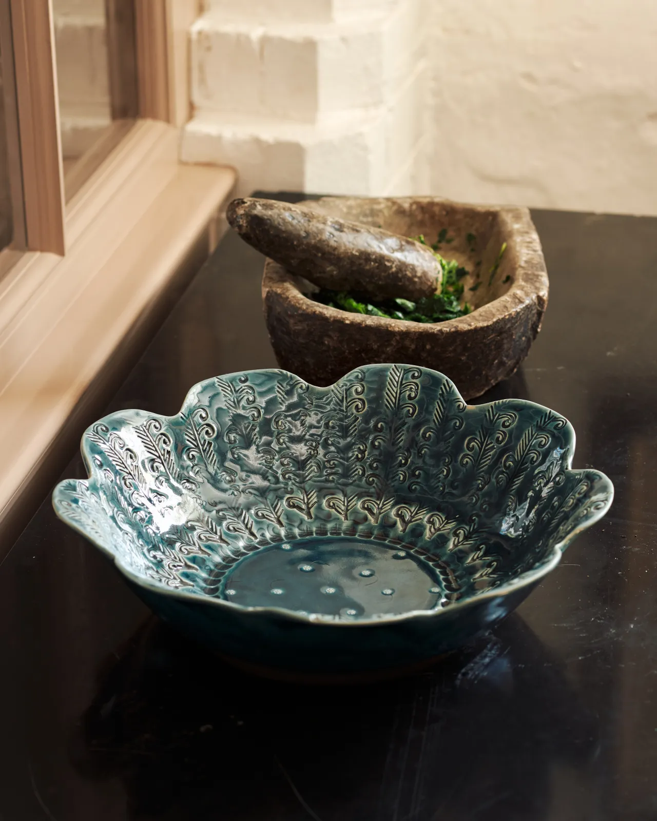 Blue glazed petal-shaped ceramic bowl with embossed pattern on a dark surface.
