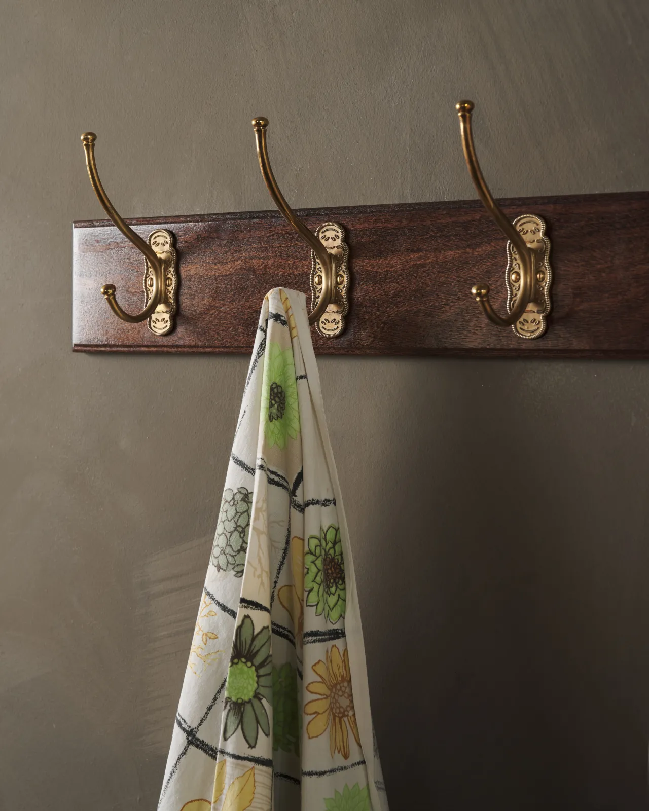 A close-up oblique view of a Mahogany Finish Hook Rack with brass Parisian Café Hooks.
