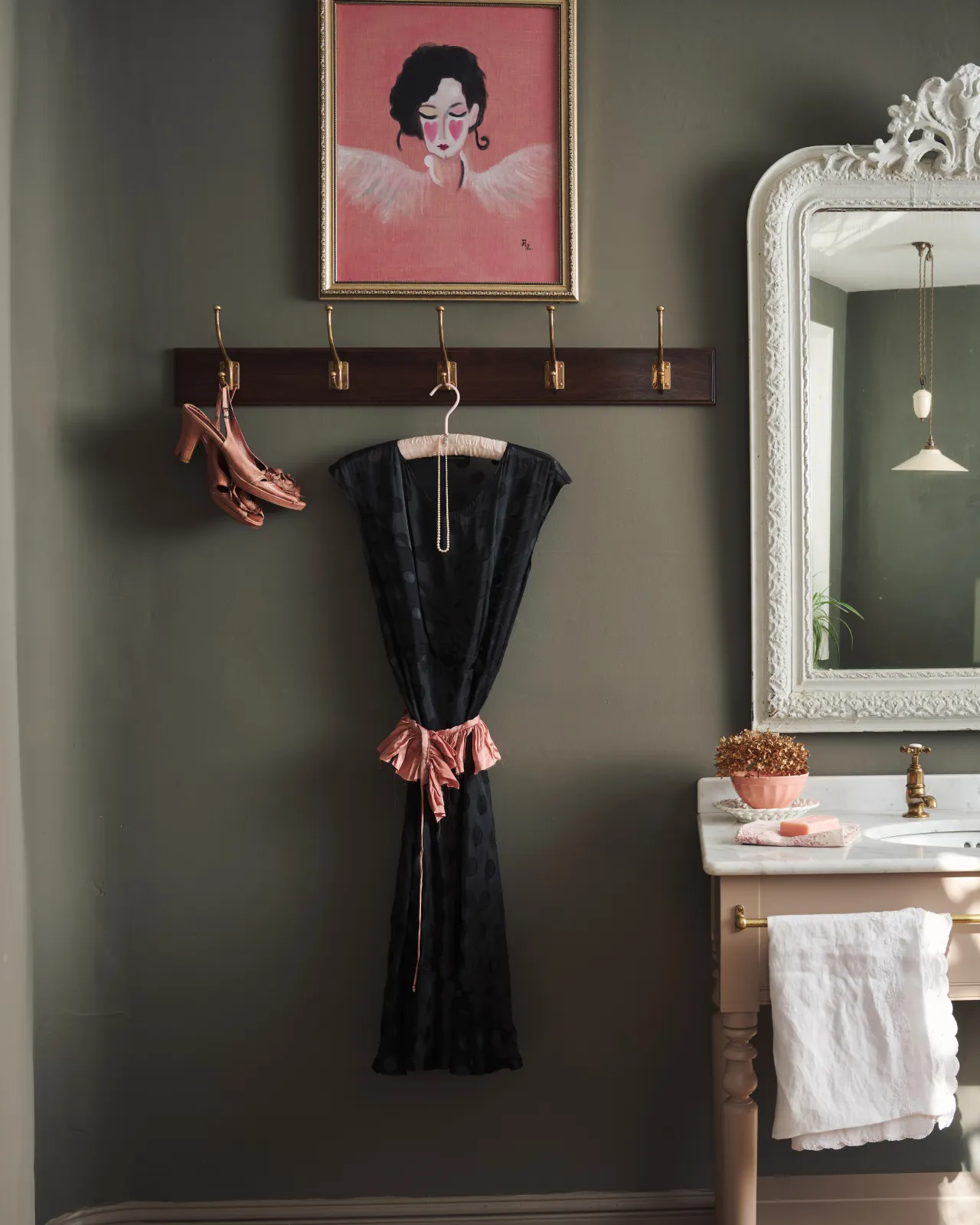 A Mahogany Finish Hook Rack with 5 Edwardian brass hooks, fitted to a moody grey wall with a black dress and dusky pink shoes hanging. A pink portrait painting and tall mirror decorate the space around the hook rack.