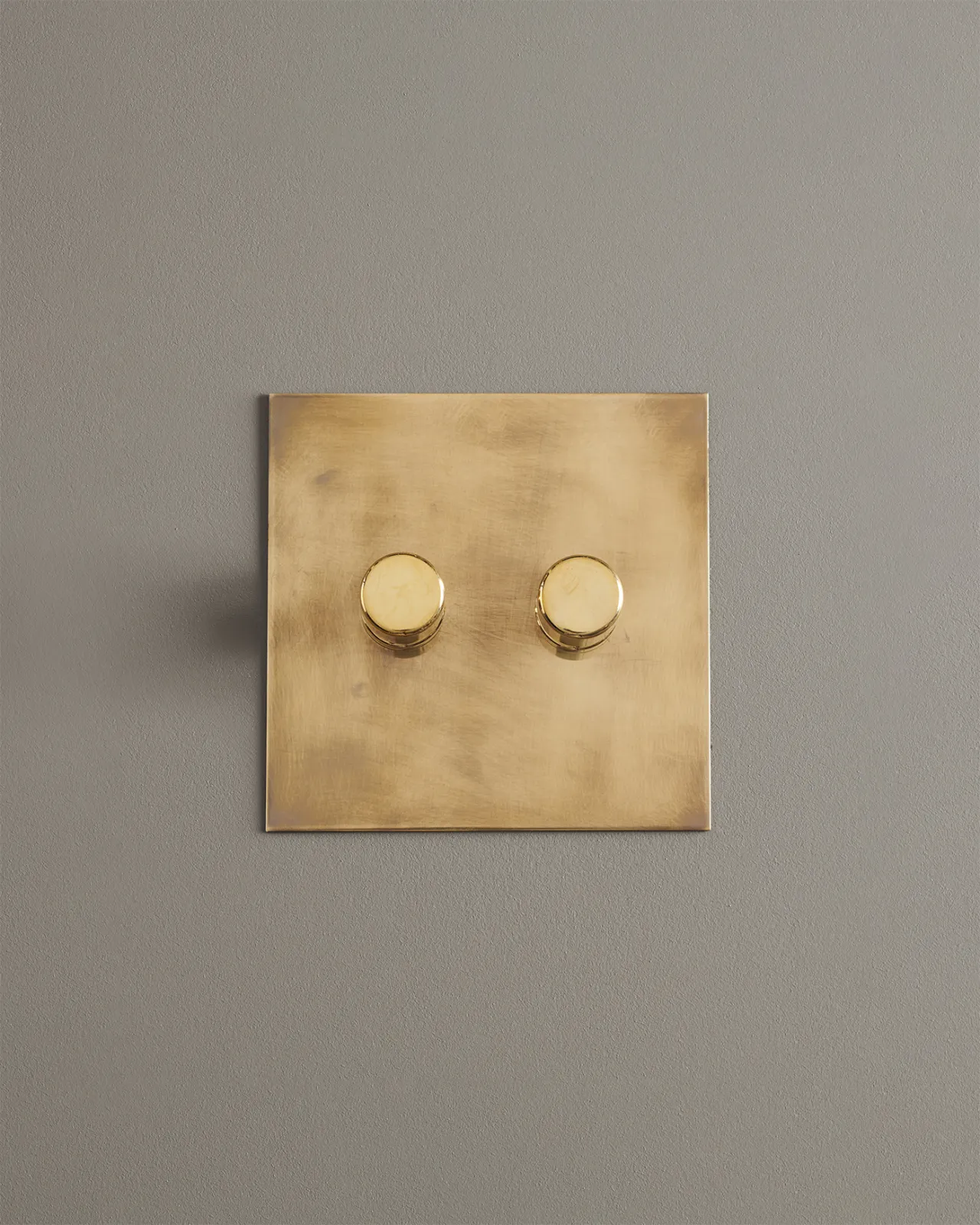 A straight-on view of a 2 gang dimmer switch in an aged brass finish.