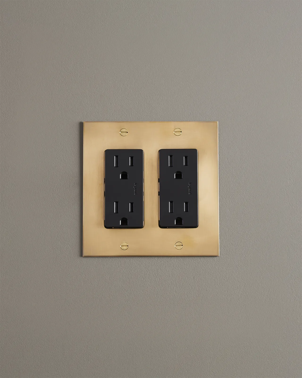 A straight-on view of a quad duplex outlet in an aged brass finish.