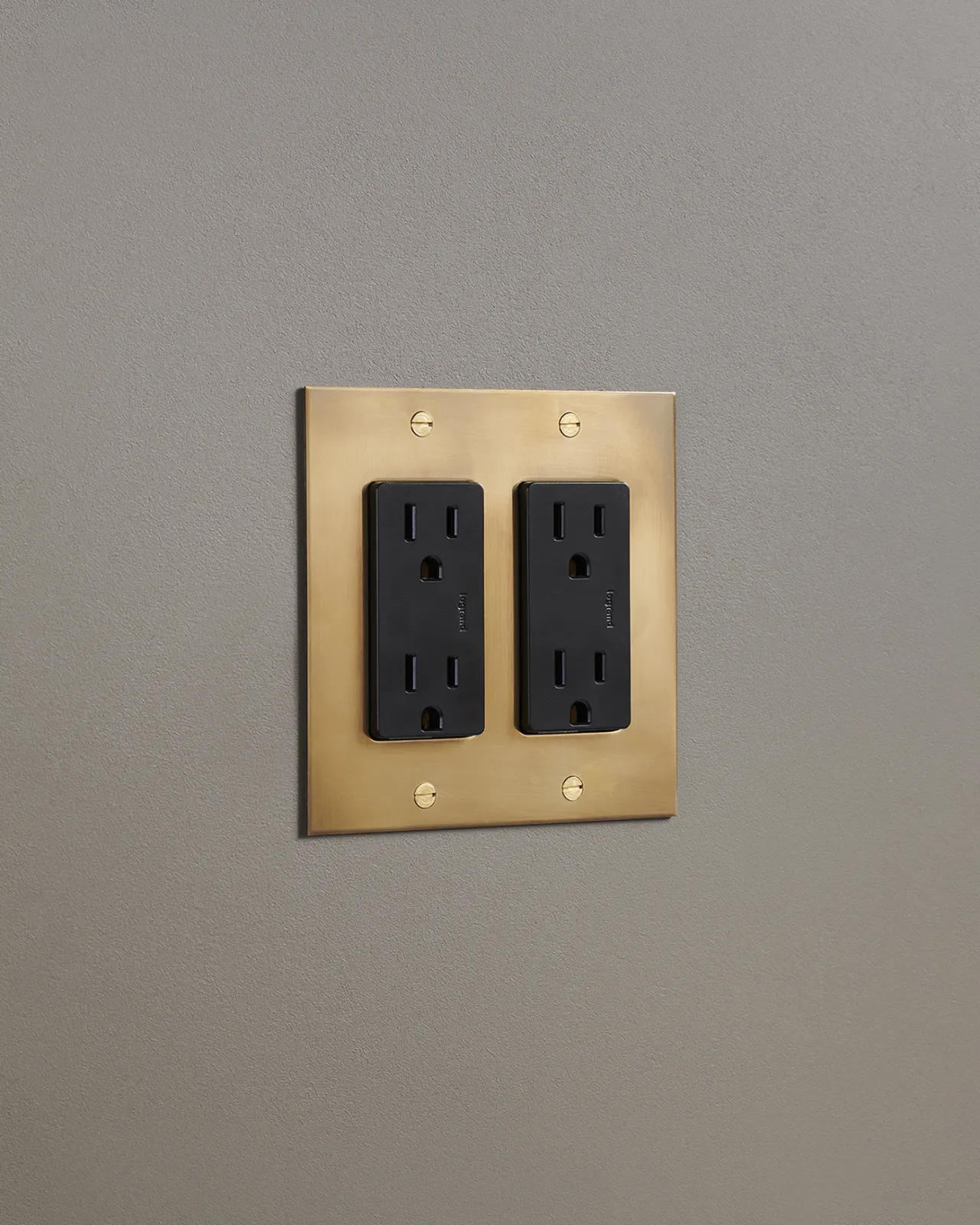 An oblique view of a quad duplex outlet in an aged brass finish.