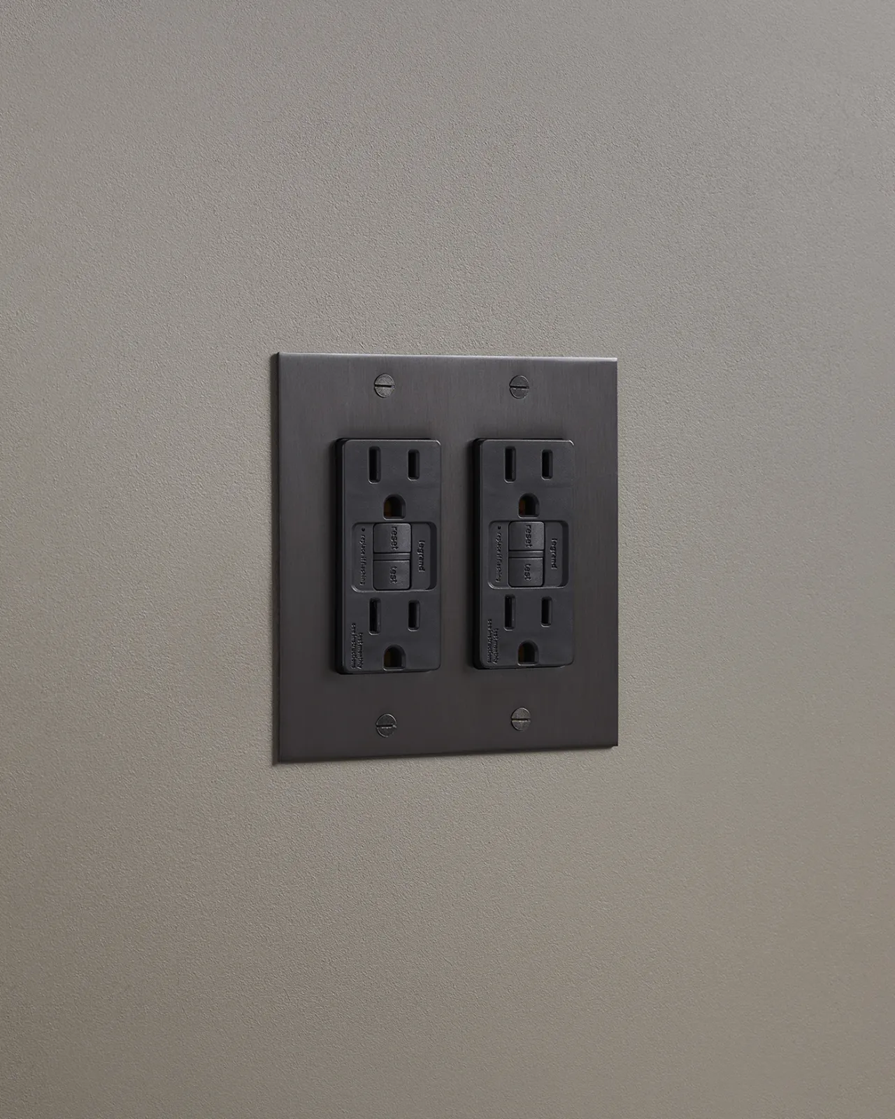An oblique view of a quad duplex GFCI outlet in an antiqued bronze finish.
