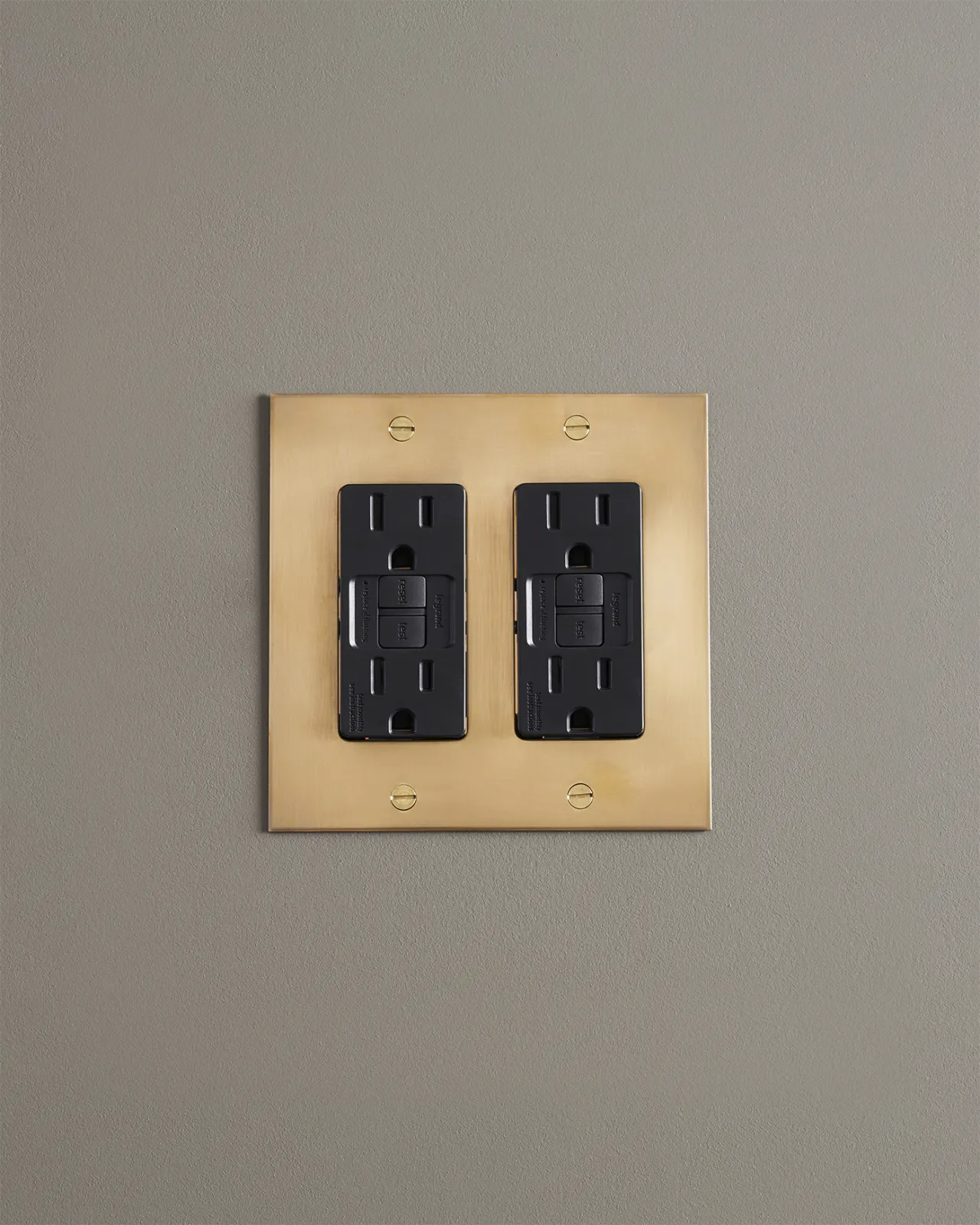 A straight-on view of a quad duplex GFCI outlet in an aged brass finish.