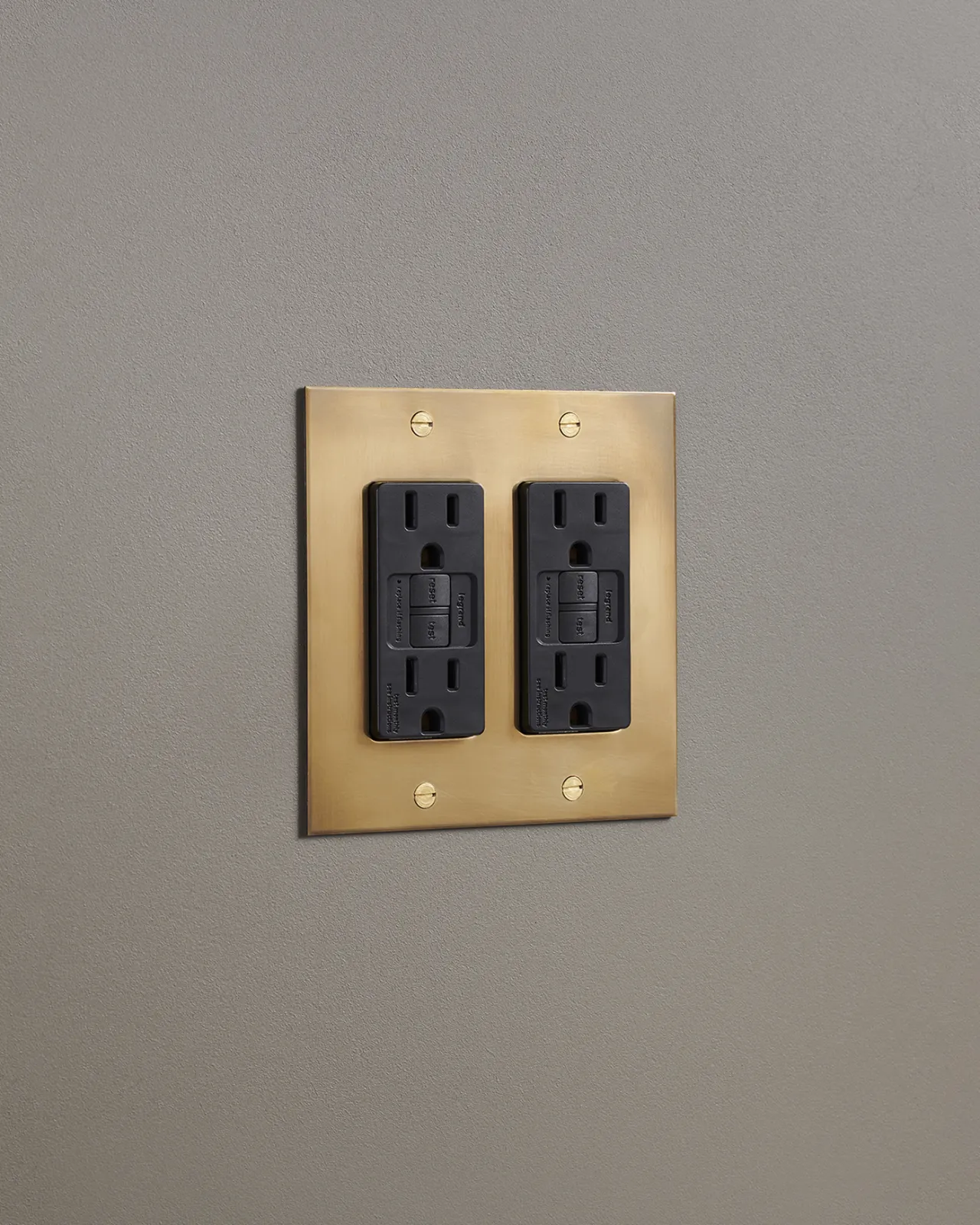 An oblique view of a quad duplex GFCI outlet in an aged brass finish.