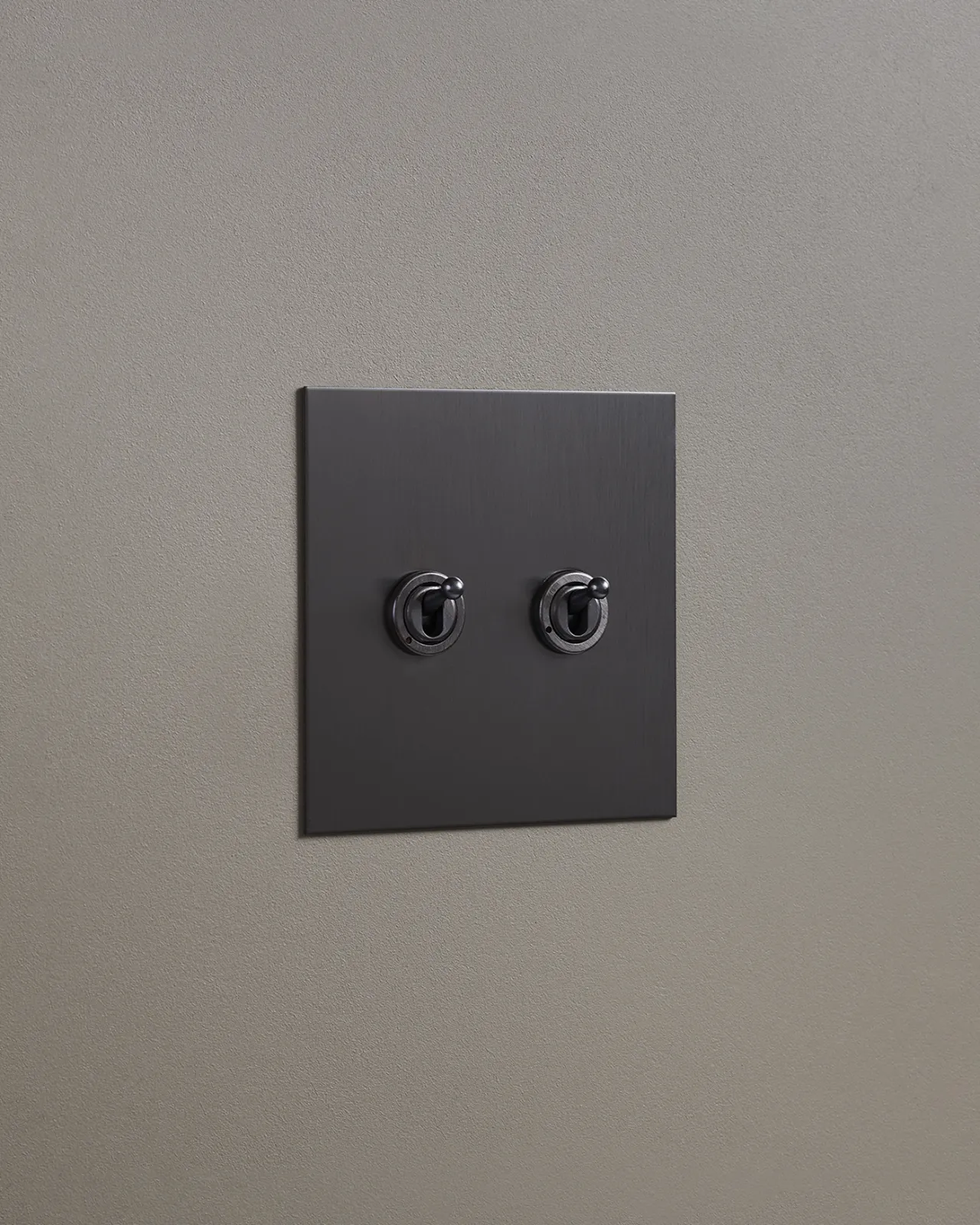 An oblique view of a 2 gang toggle switch in an antiqued bronze finish.