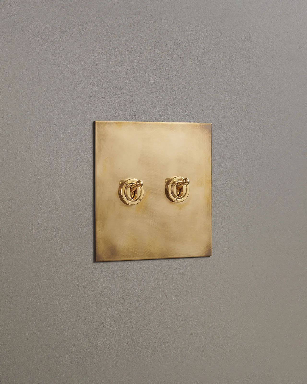 An oblique view of a 2 gang toggle switch in an aged brass finish.