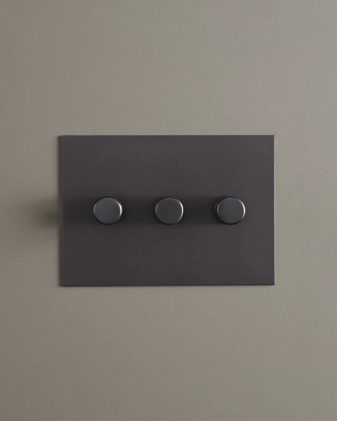 A straight-on view of a 3 gang dimmer switch in an antiqued bronze finish.