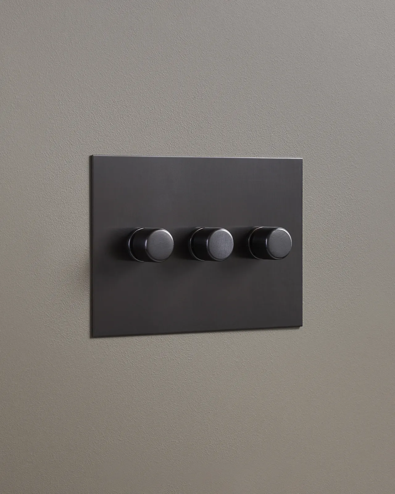 An oblique view of a 3 gang dimmer switch in an antiqued bronze finish.
