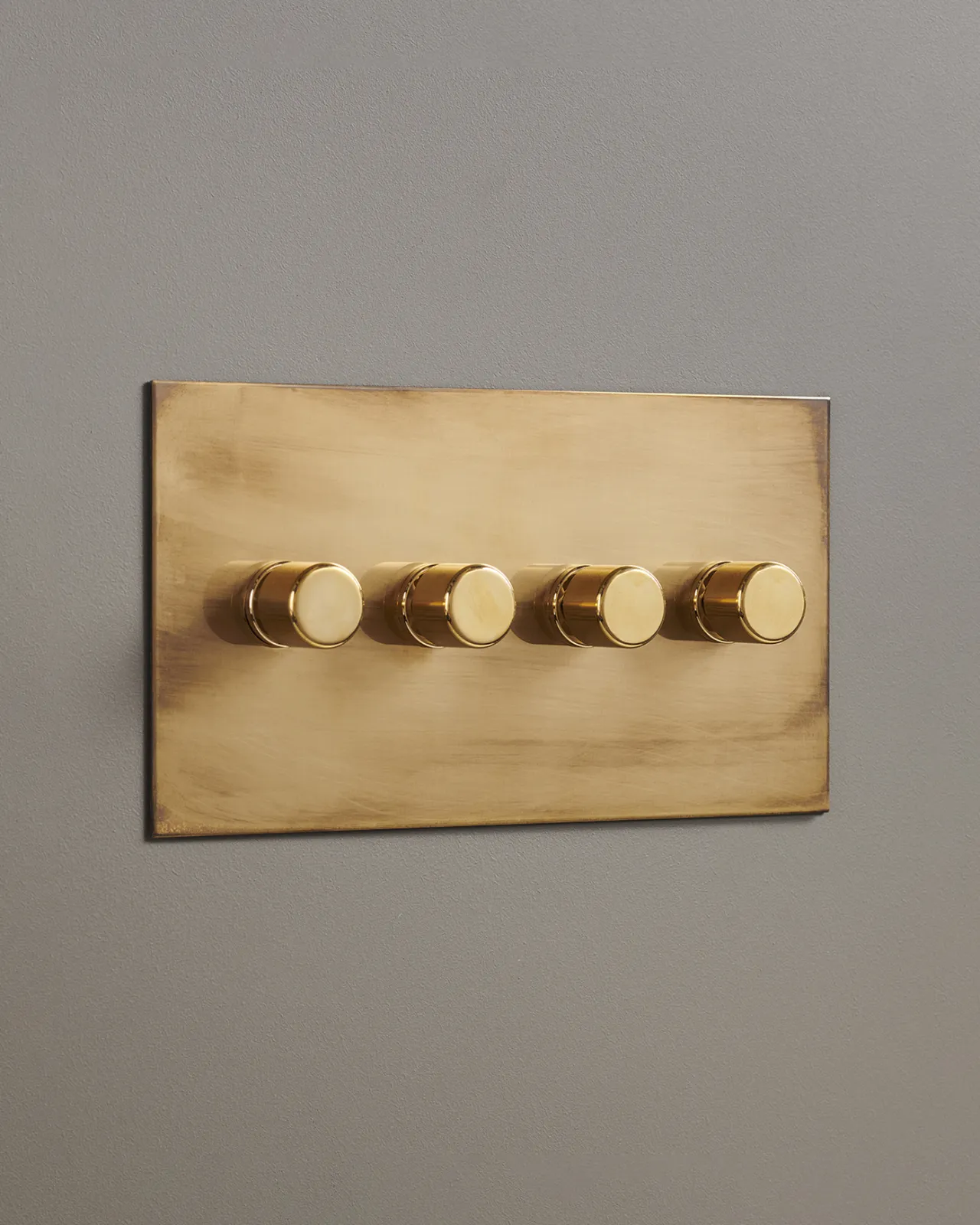 An oblique view of a 4 gang dimmer switch in an aged brass finish.