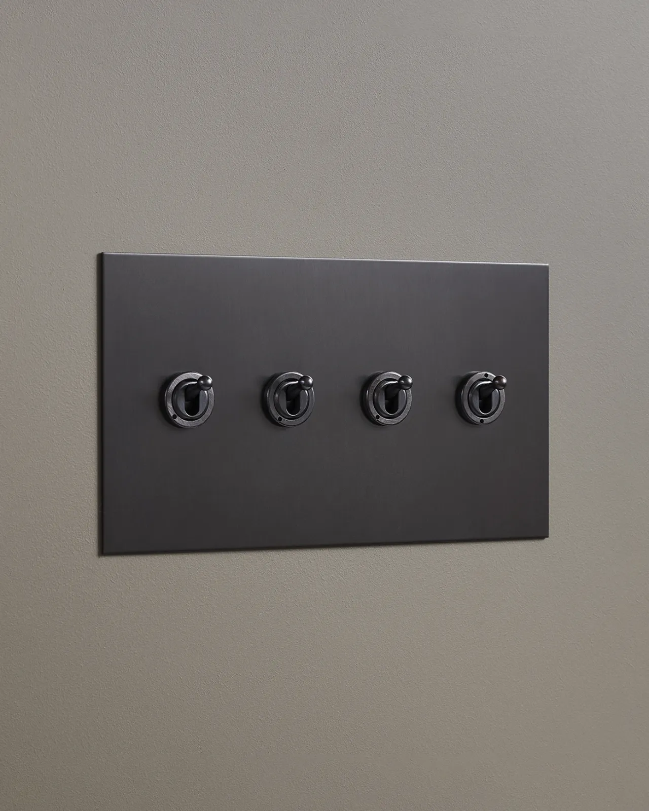 An oblique view of a 4 gang toggle switch in an antiqued bronze finish.