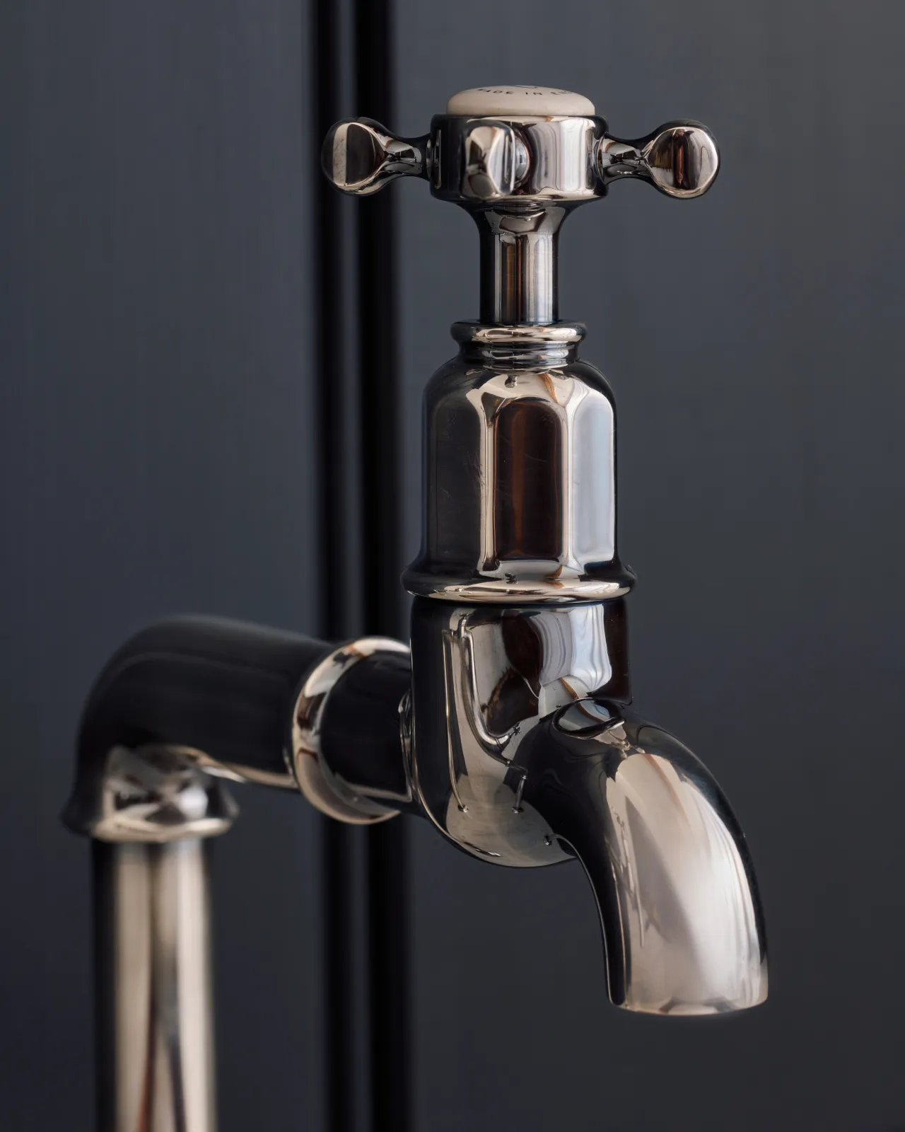 A close-up view of the head of a traditional-style tarnished silver bibcock tap with a crosshead handle.