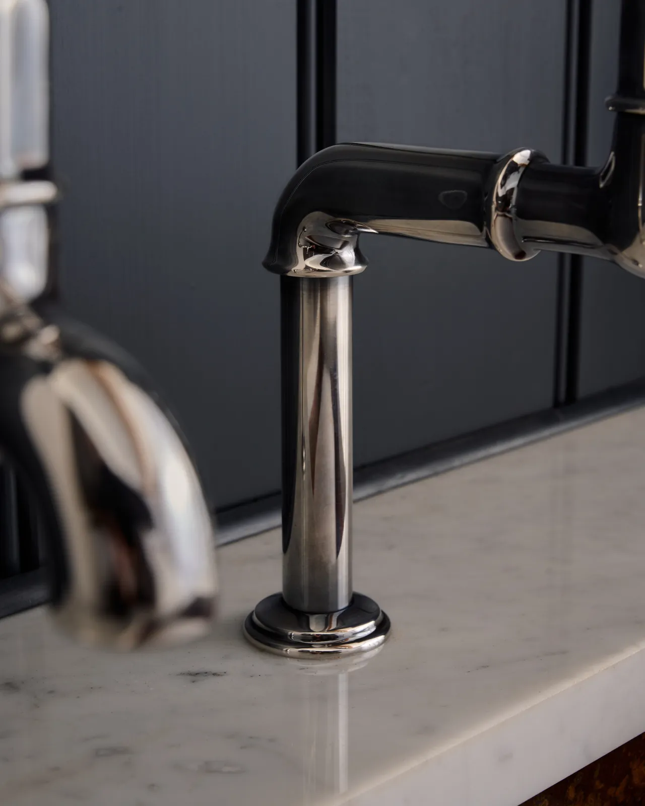 A close-up view of the base of a traditional-style tarnished silver bibcock tap.