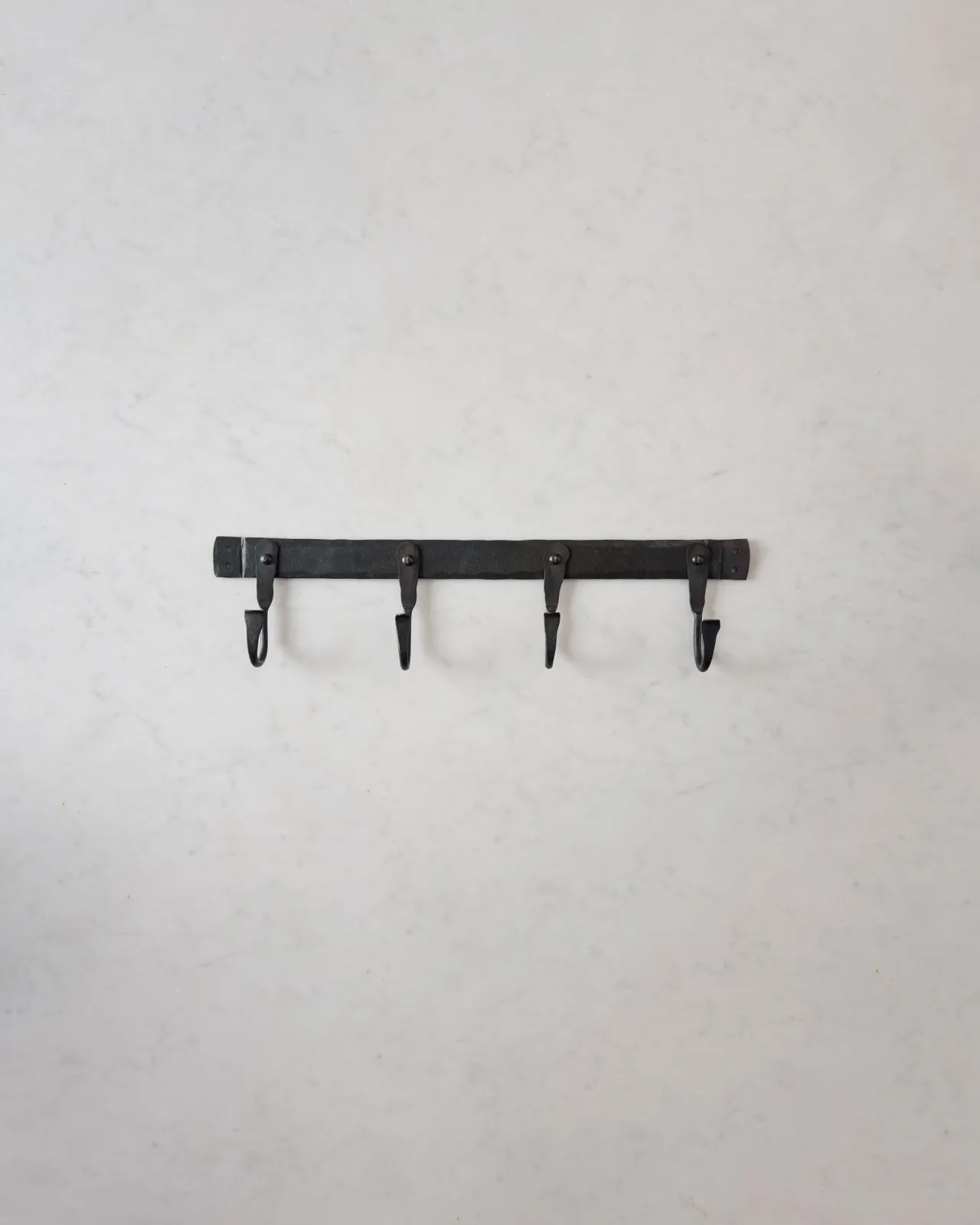 A medium iron hook rack with four hooks spread evenly across the length.