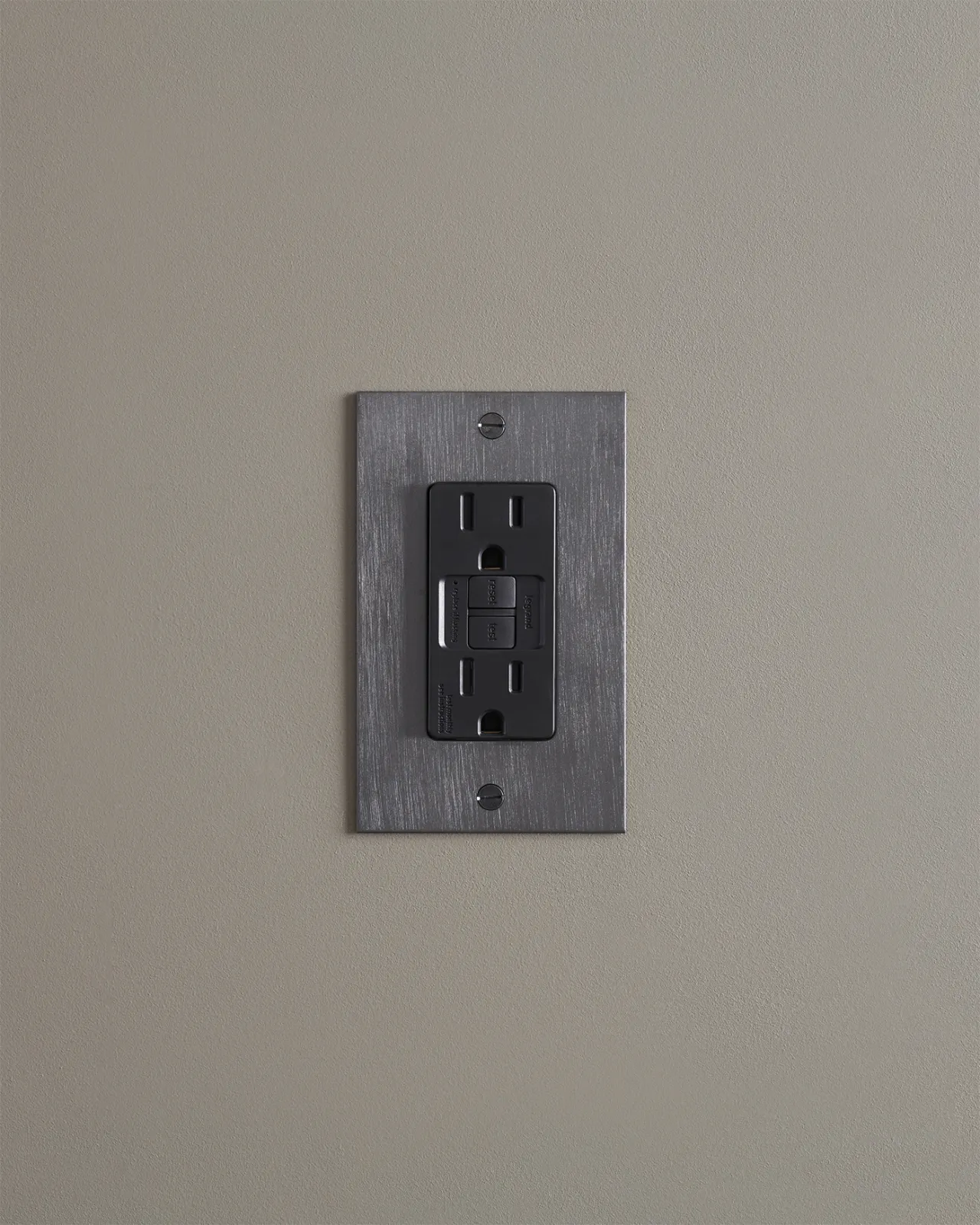 A straight-on view of a duplex GFCI outlet in an antiqued bronze finish.