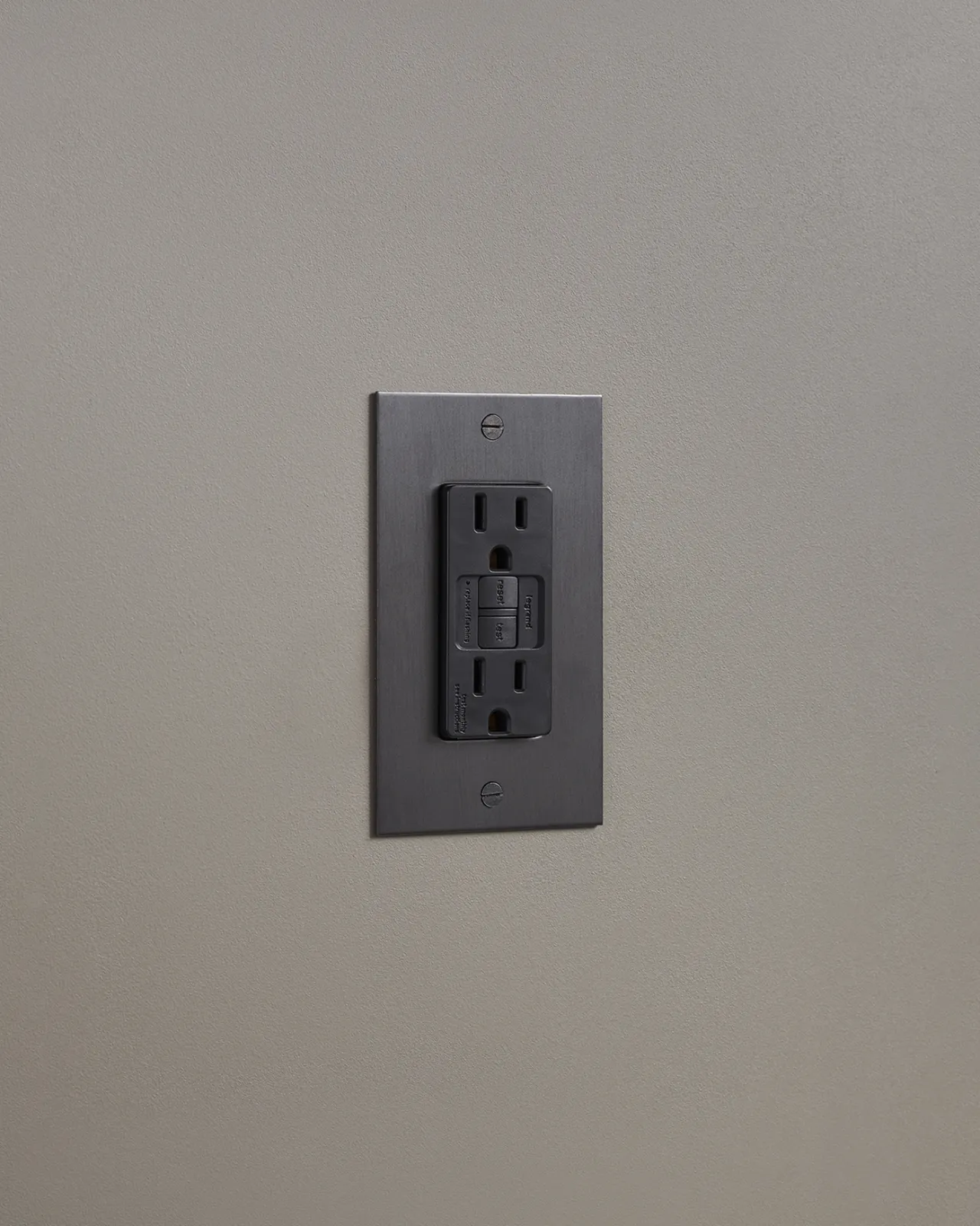 An oblique view of a duplex GFCI outlet in an antiqued bronze finish.