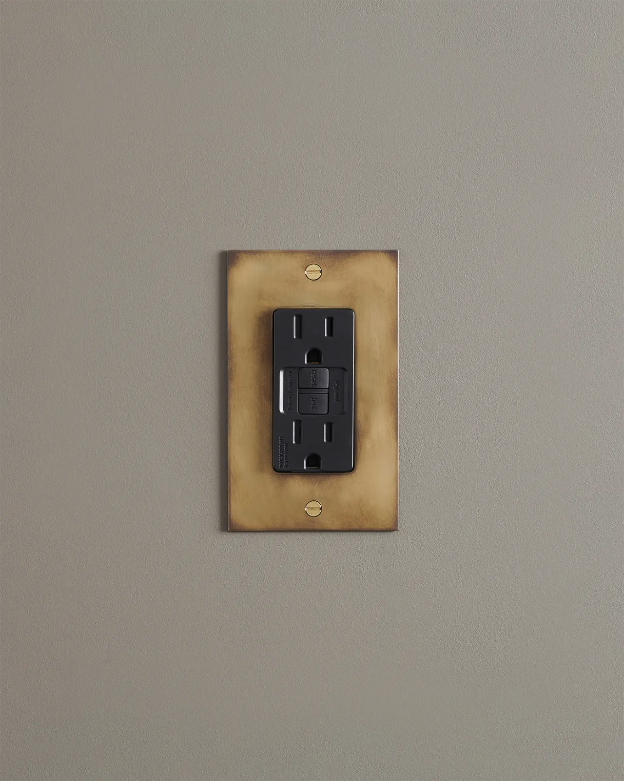 A straight-on view of a duplex GFCI outlet in an aged brass finish.