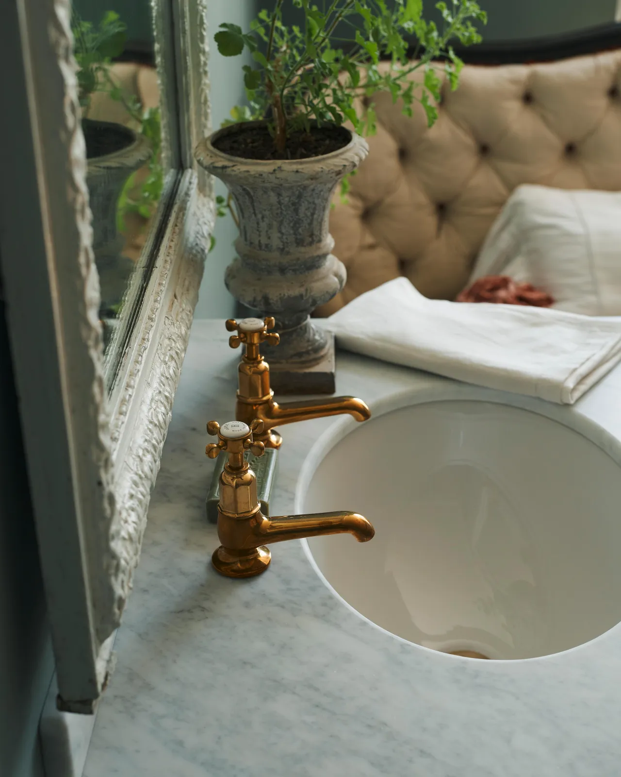 A profile view of a pair of aged brass pillar taps fitted to a bathroom washstand.