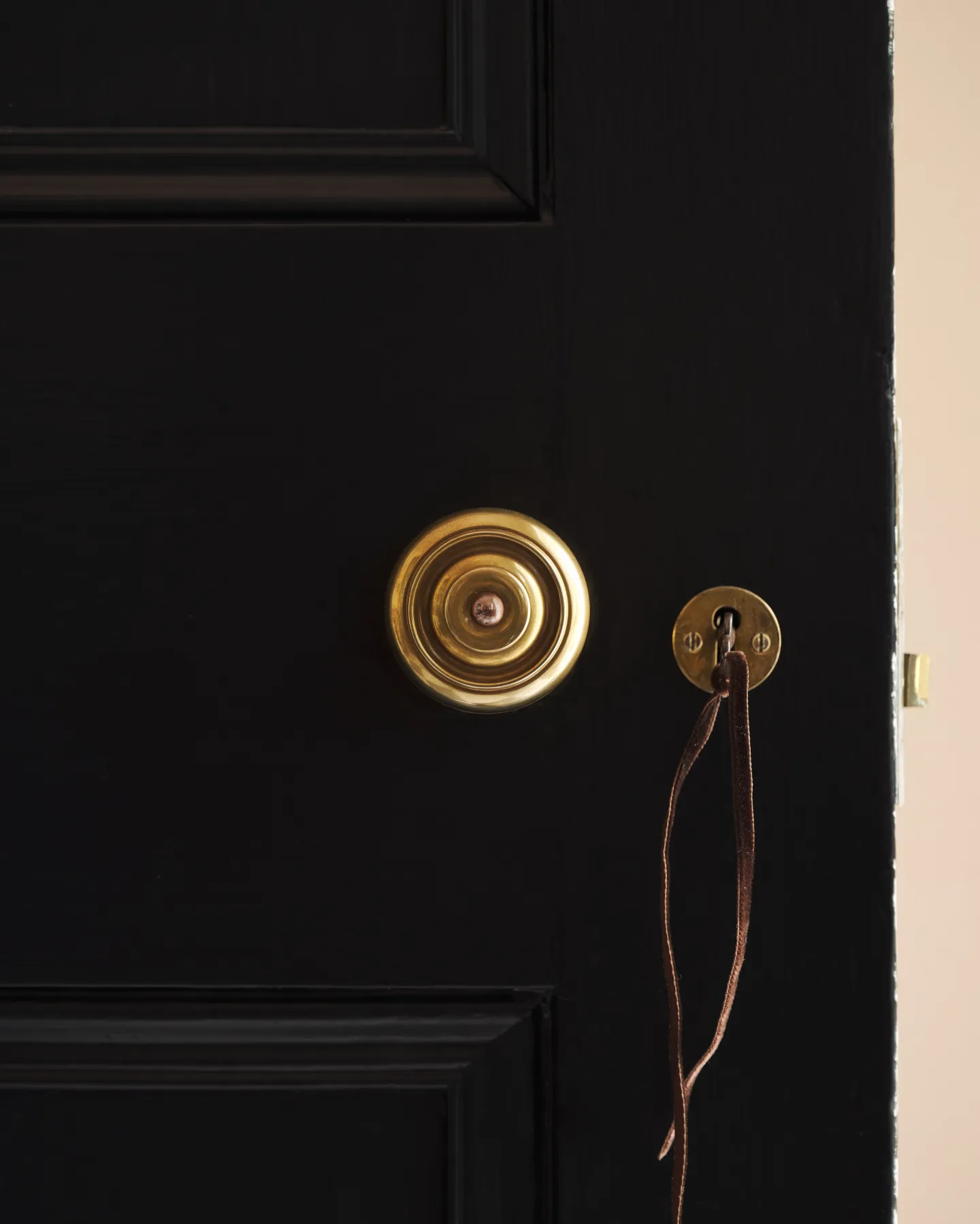 A close detail of the brass doorknob, set against the black-painted door.