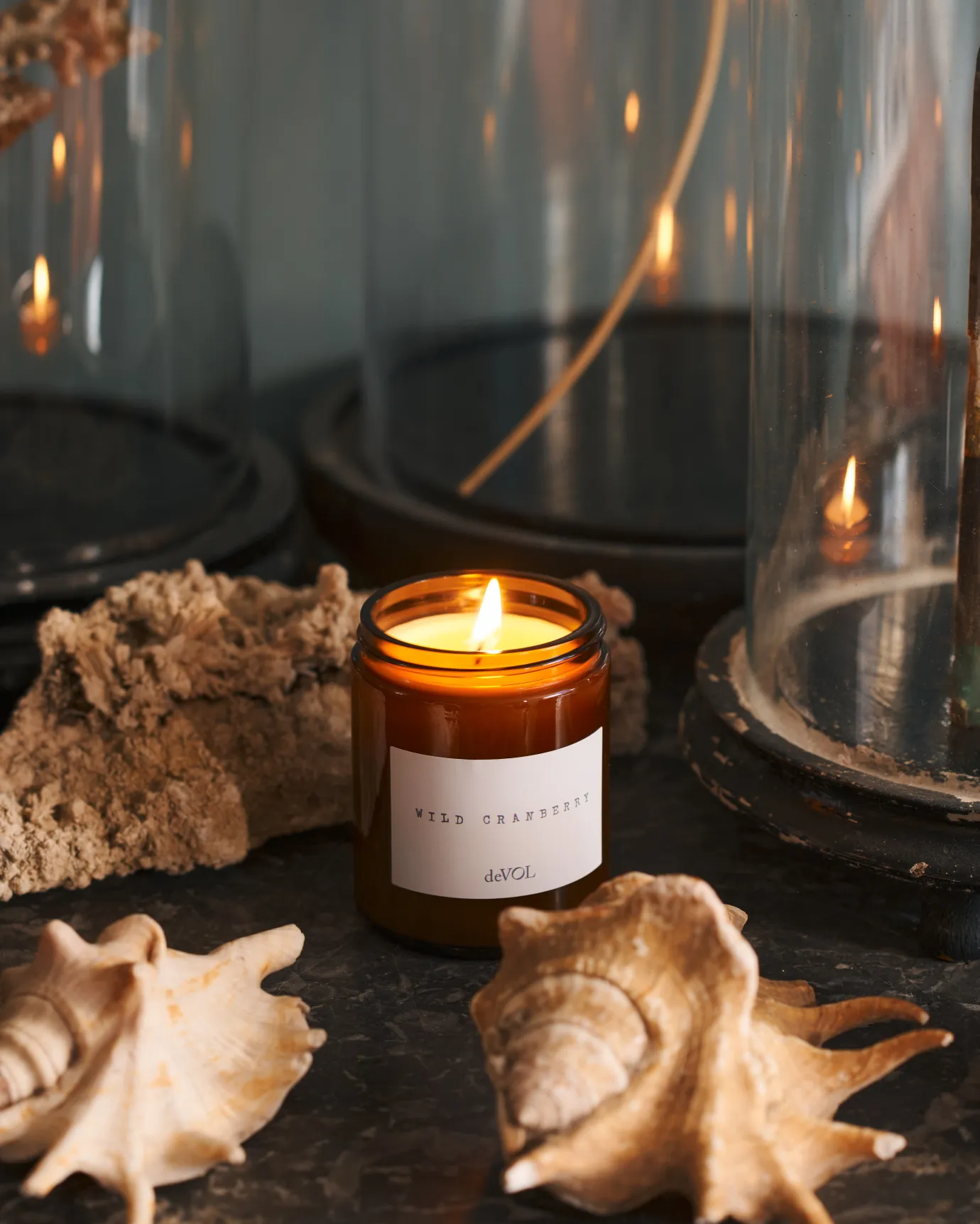 a front on shot of the medium candle surrounded by dried sea shells on a black stone top dresser.
