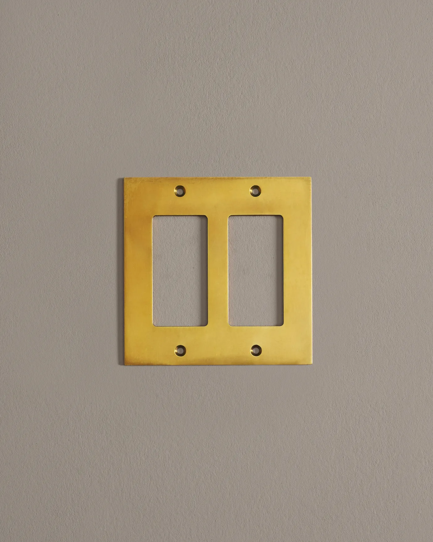 A straight-on view of a 2 gang cover plate in a warm shiny brass finish.