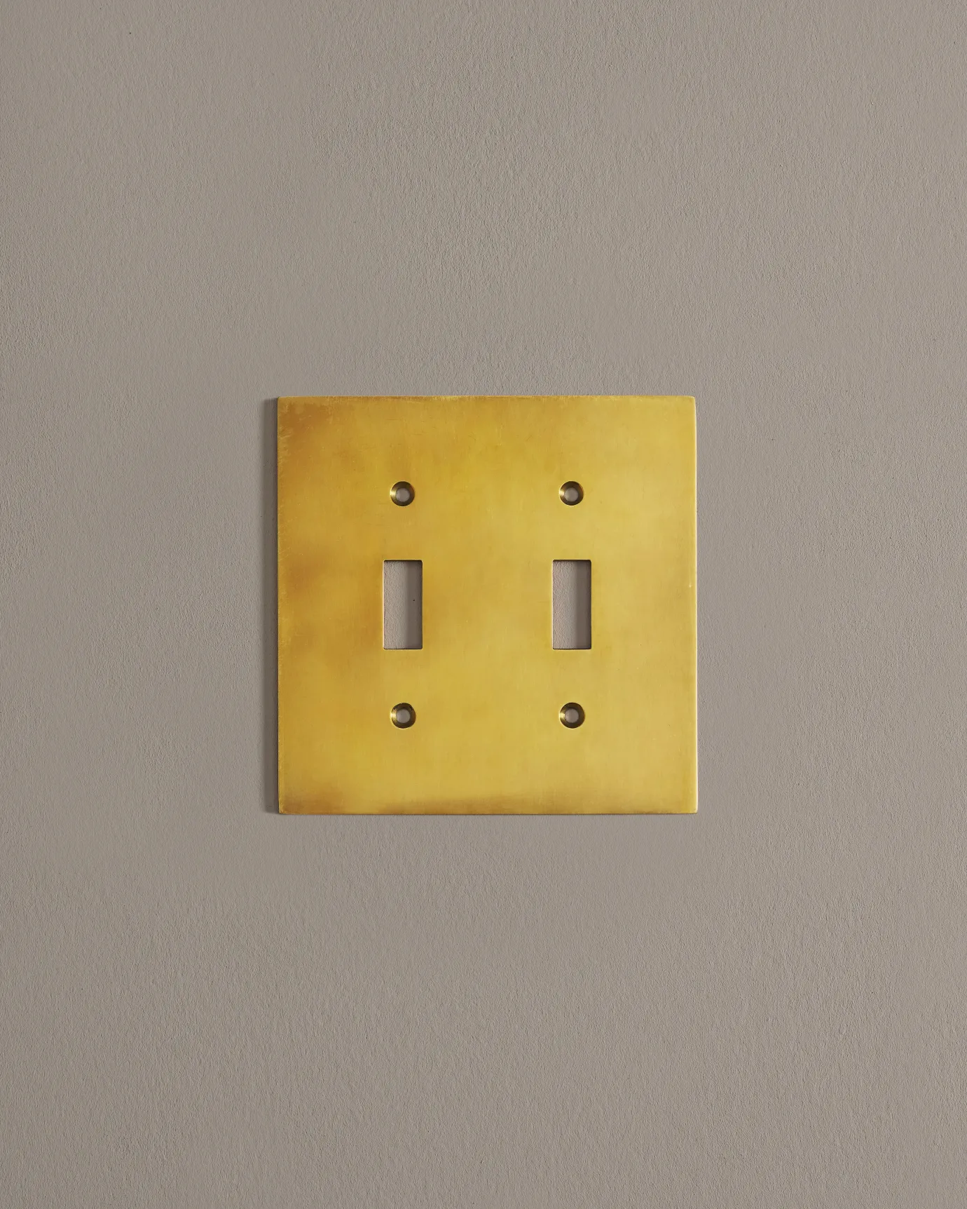 A straight-on view of a 2 gang cover plate in a warm shiny brass finish.