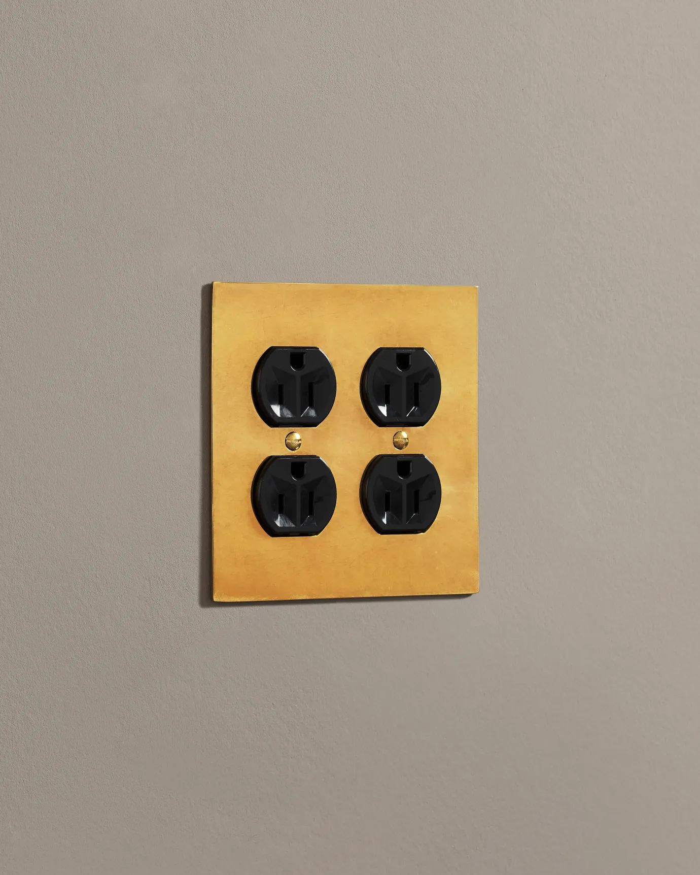 A side-on view of a 2 gang cover plate in a warm shiny brass finish with a module.