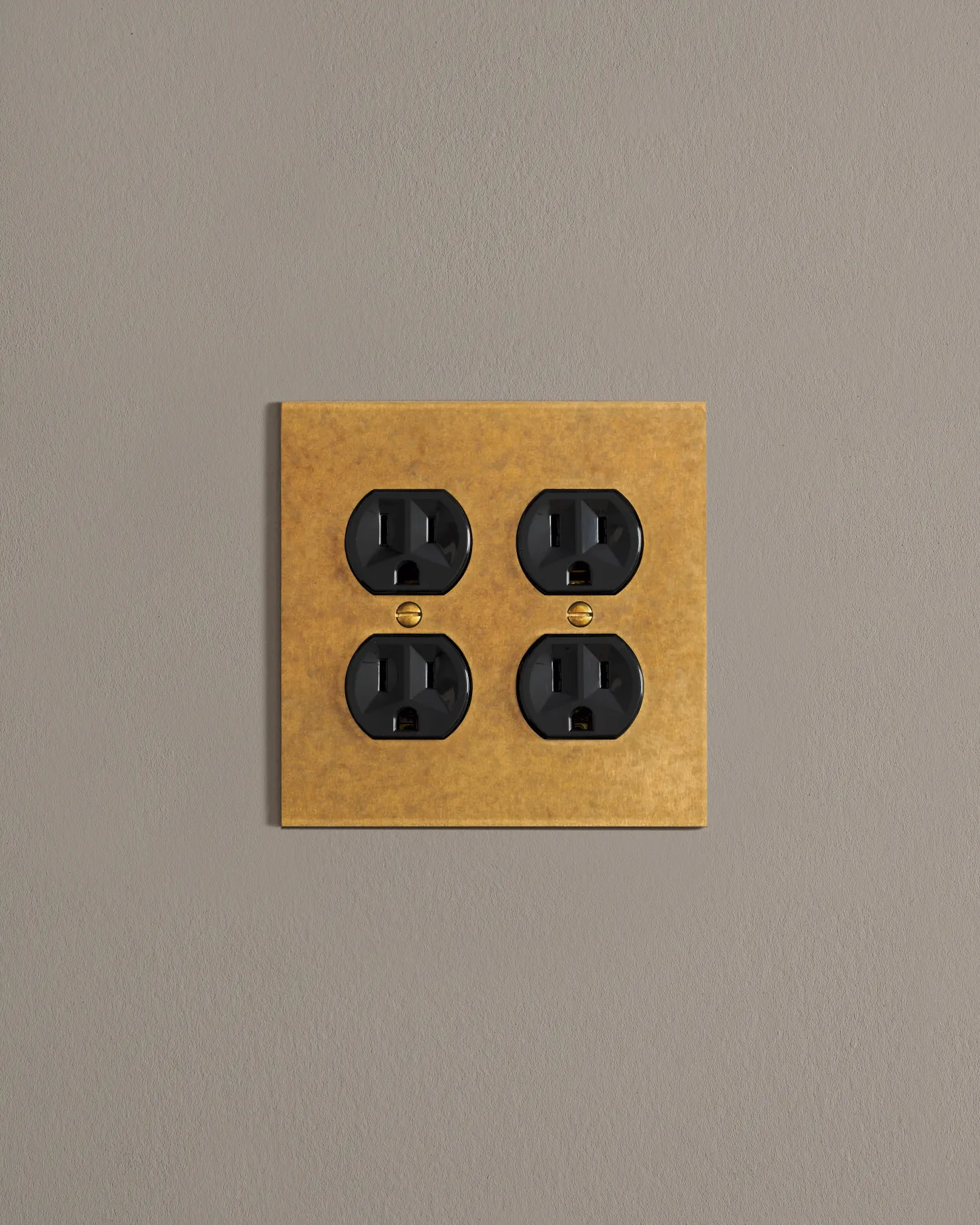 A front on shot on a duplex outlet on an aged brass cover plate.