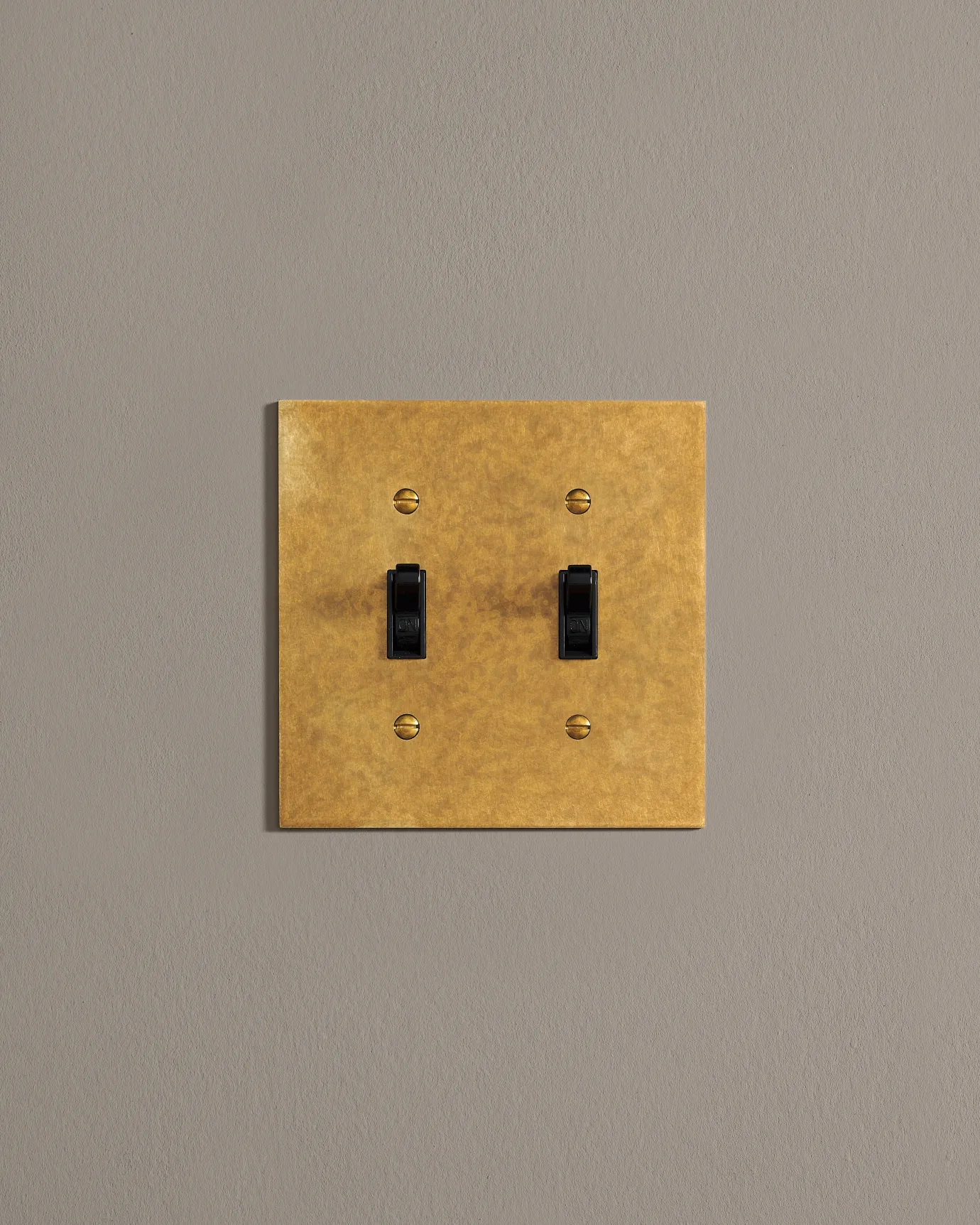 A front on shot on a toggle switch on an aged brass cover plate.