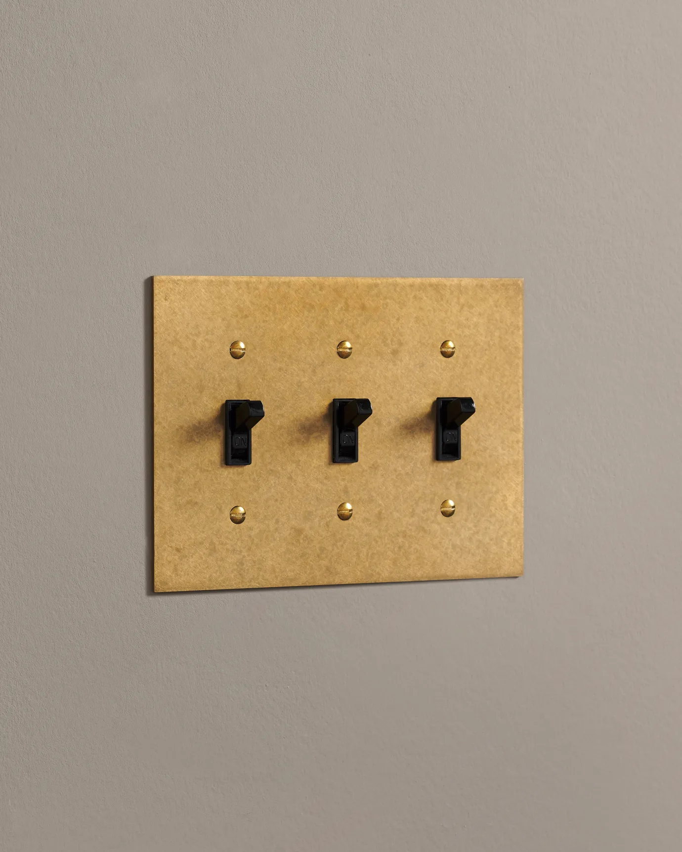 A side on shot on a toggle switch on an aged brass cover plate.