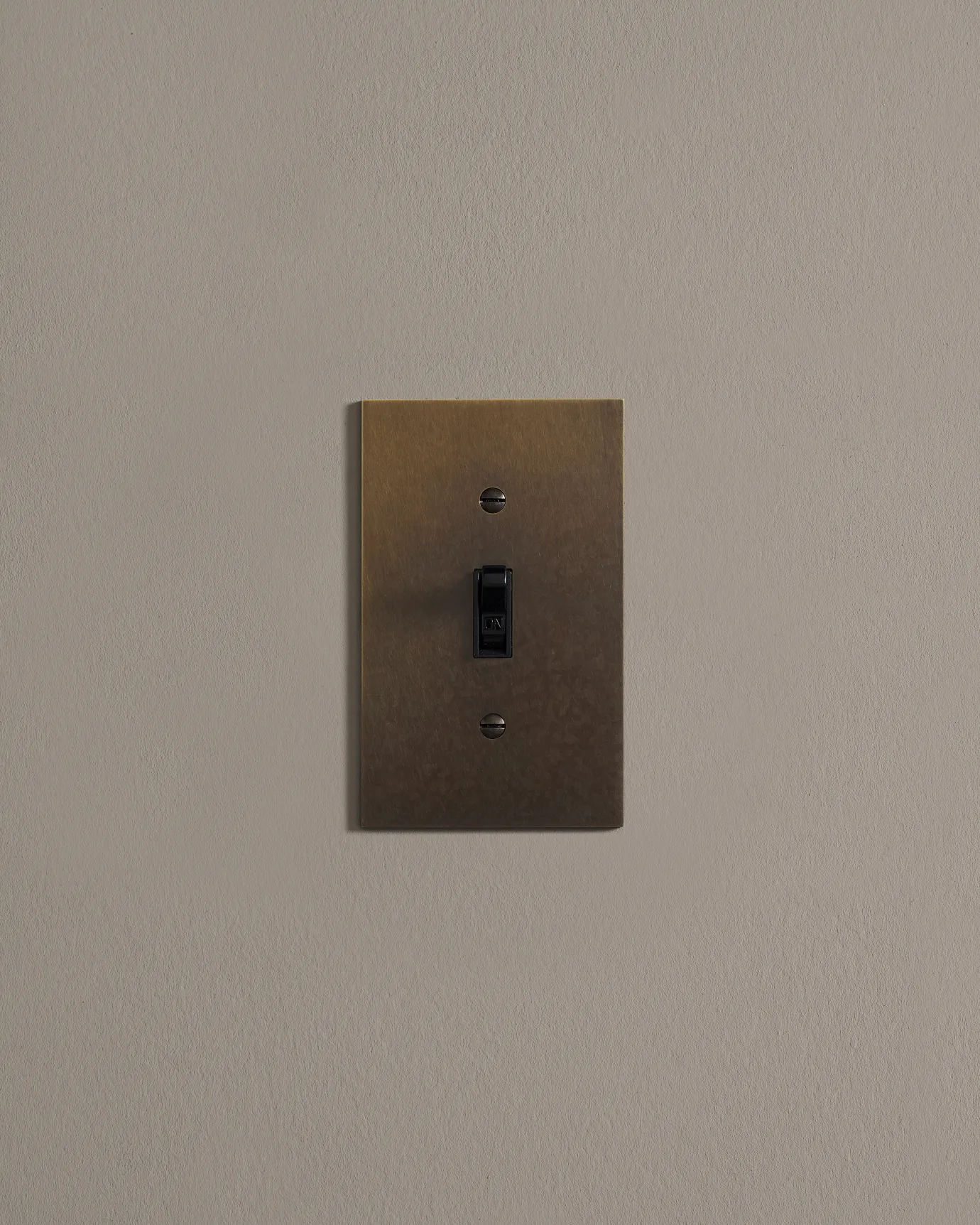a front on shot of the toggle switch on an oxidised brass cover plate.