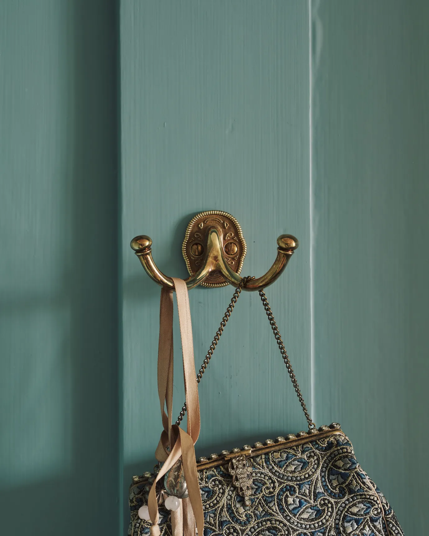 A Parisian bohemian-style twin brass hook, fitted to a blue painted door.