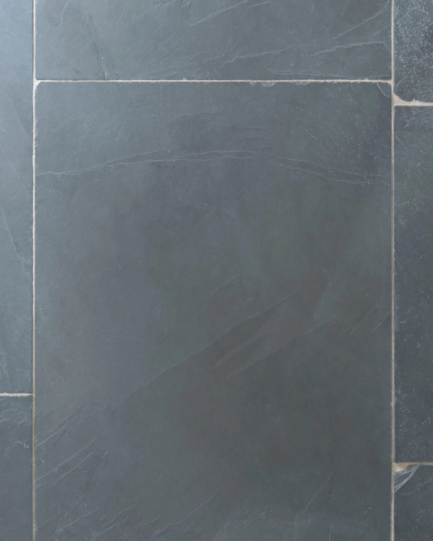 A close-up overhead view of a grey tumbled slate floor.